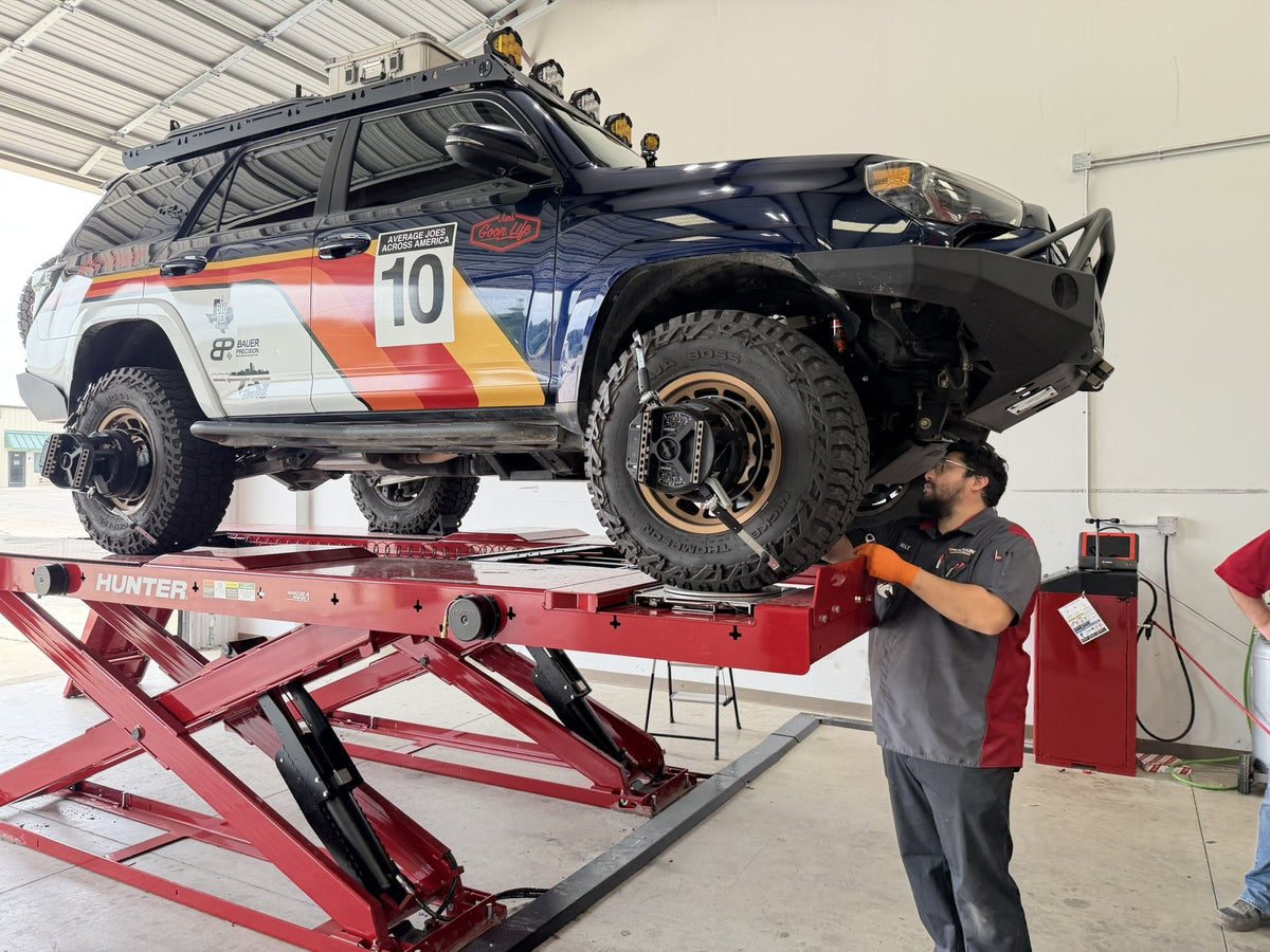 Technician working on a rally-livery 4Runner on the Hunter alignment lift